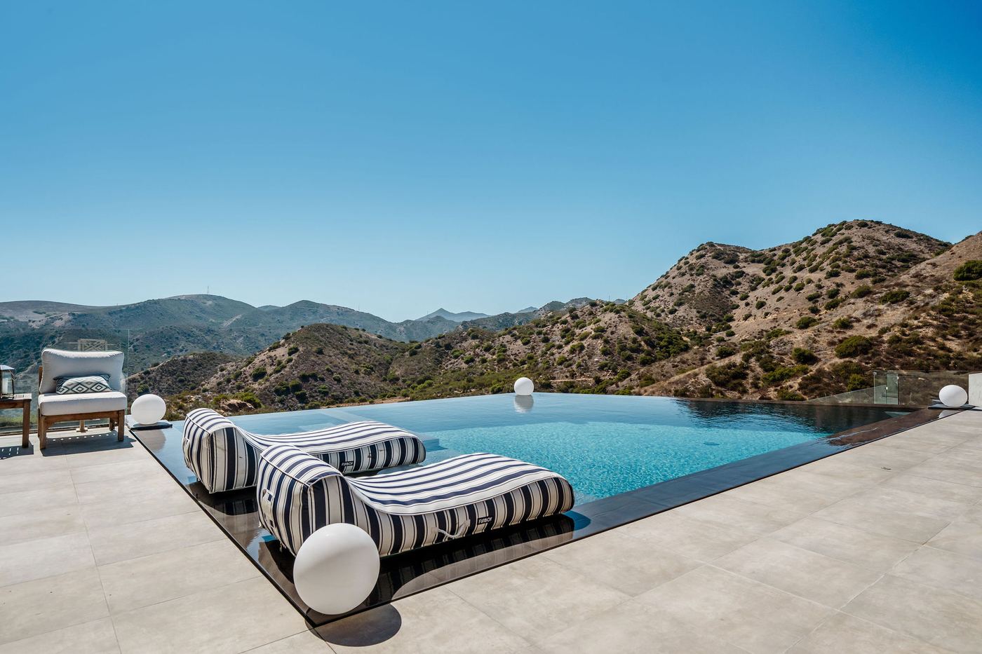 Zero-edge infinity pool at 9 Morgan Rd in Bell Canyon with striped loungers and mountains beyond