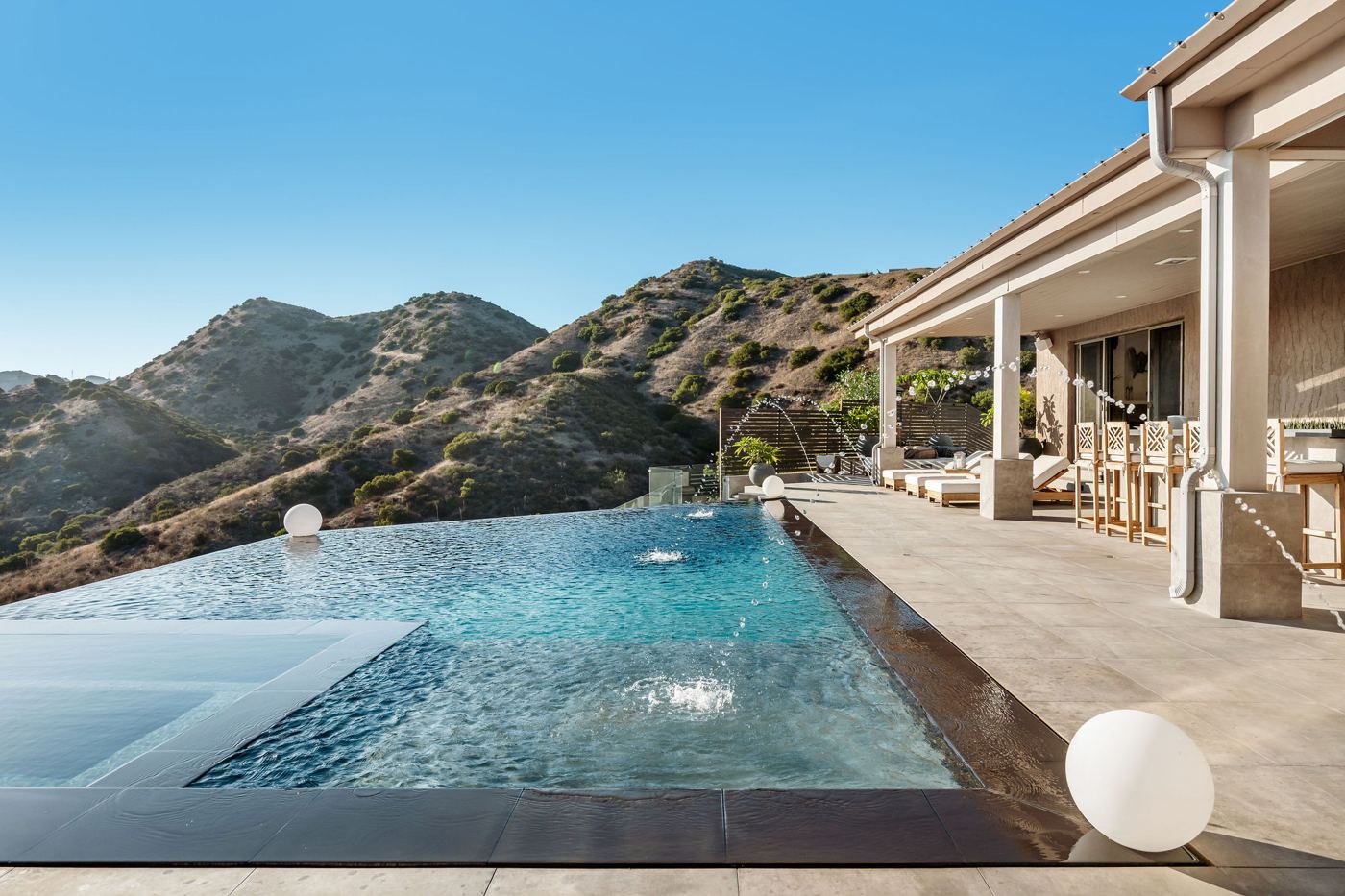 Zero-edge infinity pool at 9 Morgan Rd with a covered patio and mountain backdrop
