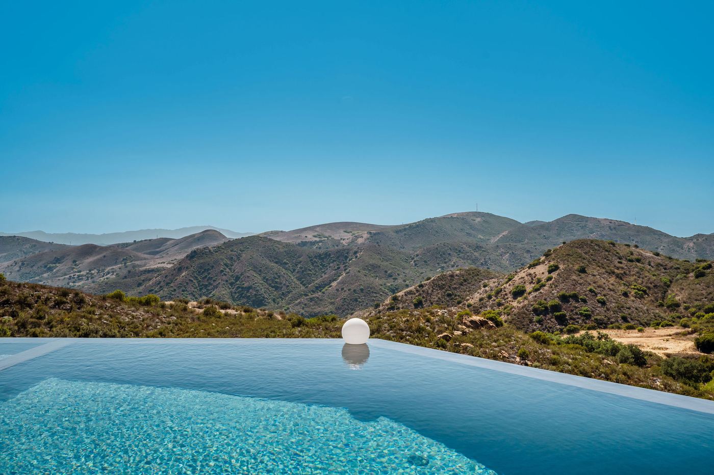 View from the edge of the infinity pool at 9 Morgan Rd across canyon hillsides to distant mountains